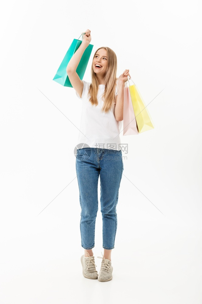 一名带着购物袋孤立在白色背景上的美丽年轻女完整肖像一名带着购物袋孤立在白色背景上的美丽年轻女完整肖像图片