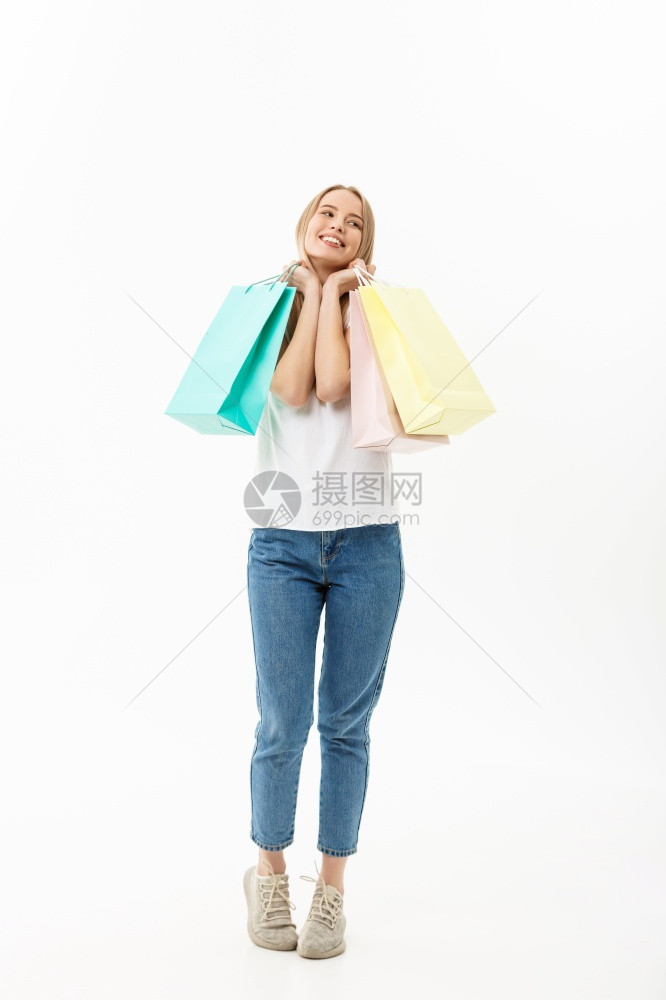 一名带着购物袋孤立在白色背景上的美丽年轻女完整肖像一名带着购物袋孤立在白色背景上的美丽年轻女完整肖像图片