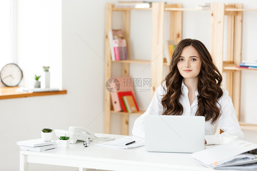 年轻漂亮的商业妇女笔记本和文件在明亮的现代办公室内明亮的现代办公室图片