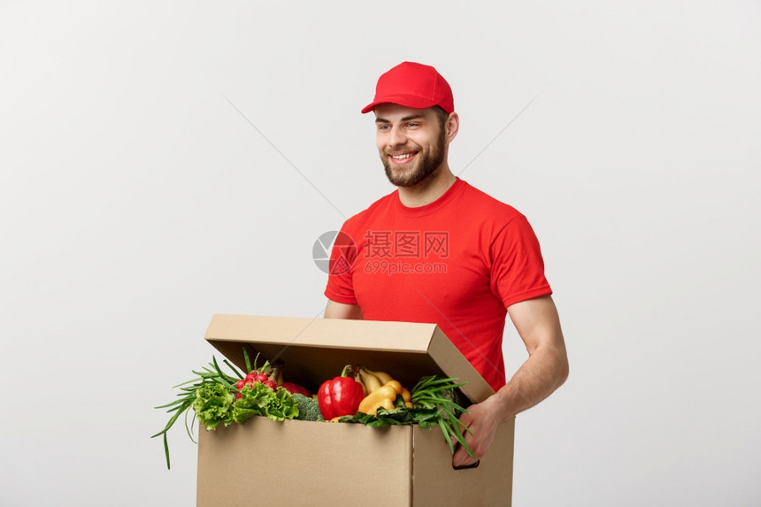 交付概念英俊的天主教杂货送员穿红色制服配有新鲜水果和蔬菜的杂货箱交付概念英俊的天主教杂货送员穿红色制服装有新鲜水果和蔬菜的杂货箱图片