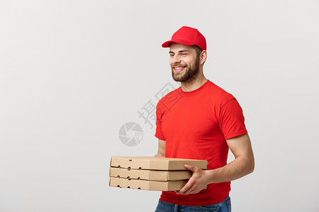 交付概念年轻的causin英俊的送披萨员拿着盒与灰色背景隔绝英俊的比萨递员与灰色背景隔绝的披萨盒背景图片