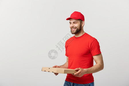 交付概念年轻大猩英俊的比萨饼送货员手持披萨盒与灰色背景隔开交付概念年轻大猩英俊的比萨饼送货员手持灰色背景隔开的比萨盒背景图片