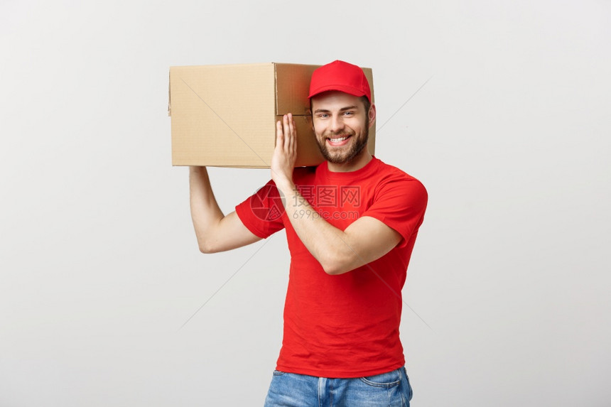 交付概念年轻的causin英俊送货员肩上拿着一个盒子被灰色背景隔开交付概念年轻的causin英俊送货员肩上拿着一个盒子被灰色背景图片