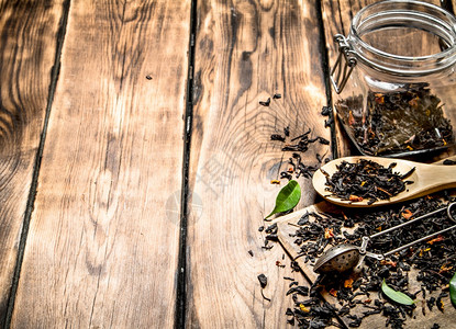 含茶匙和绿叶子的干茶罐木制背景干茶罐图片