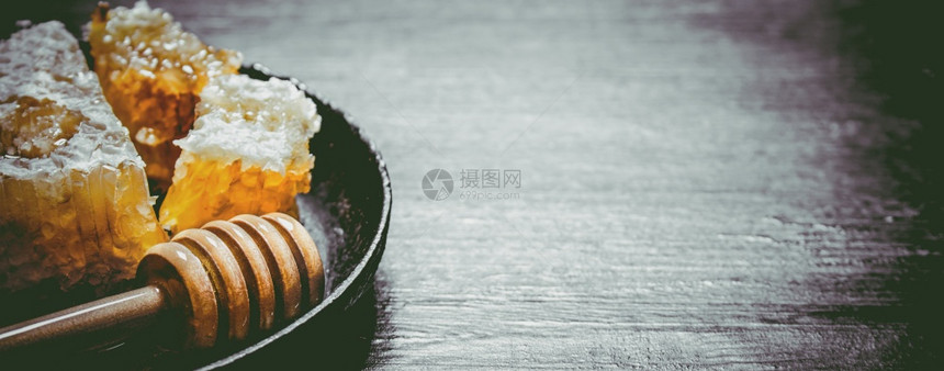 梳子里有甜的蜂蜜锅里有勺子黑生锈背景的图片