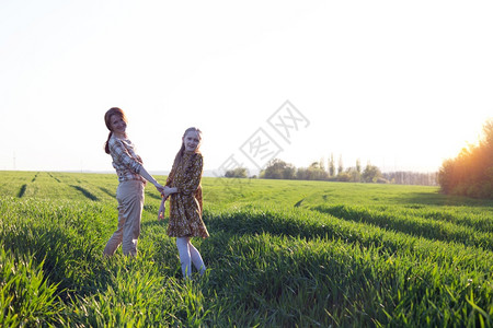家庭幸福的母亲和女儿在日落的田地上图片