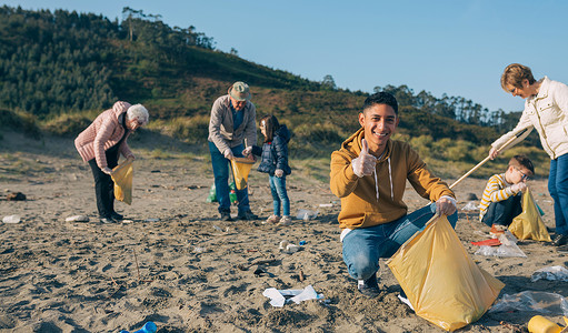 年轻人在海滩上和一群志愿者起捡垃圾图片