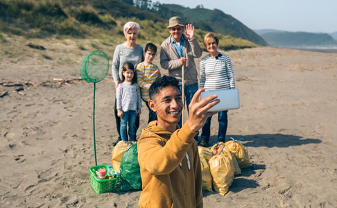 青年男子在清理海滩后将自拍与愿者团体在清理海滩后图片
