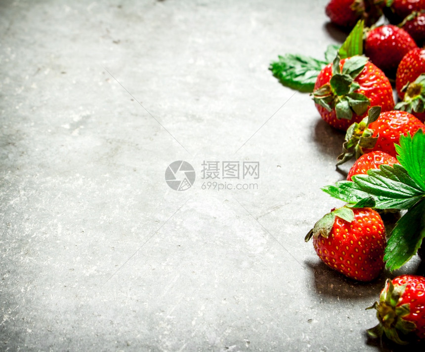 草莓和绿叶放在石板上图片