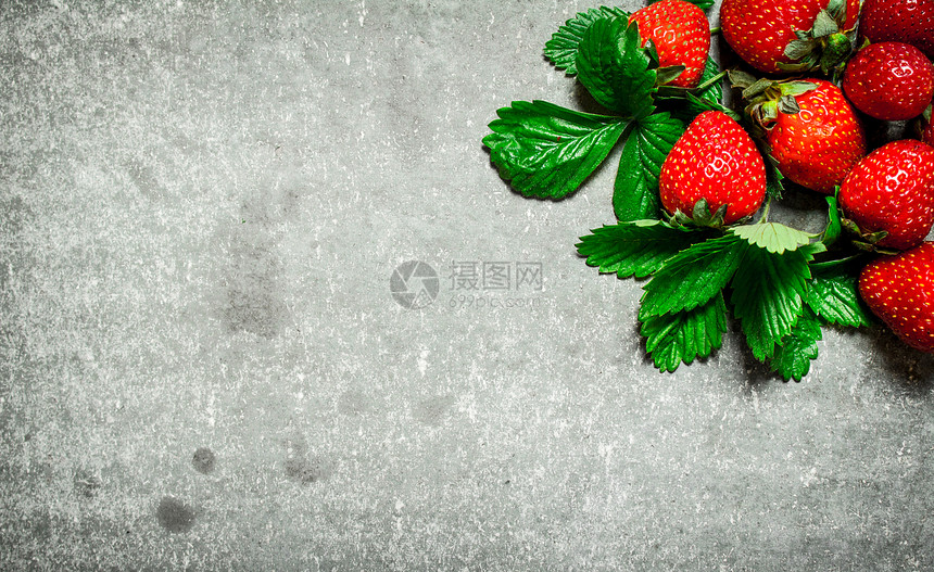 草莓和绿叶放在石板上图片