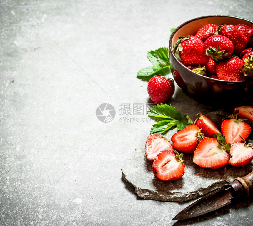 成熟的草莓和一把旧刀在石板上图片