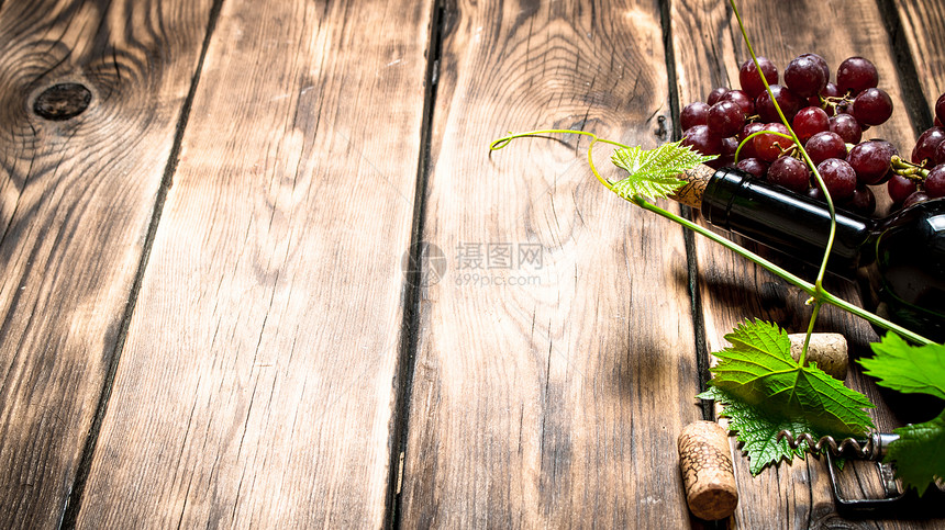 酒瓶红葡萄卷在木制桌子上葡萄卷起来图片
