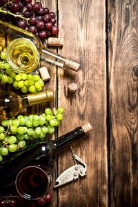 白葡萄酒和红枝木桌上的软酒和白葡萄和红图片