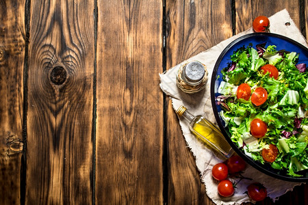 番茄加沙拉和含橄榄油的新鲜绿菜在木制桌上沙拉加番茄和绿色图片