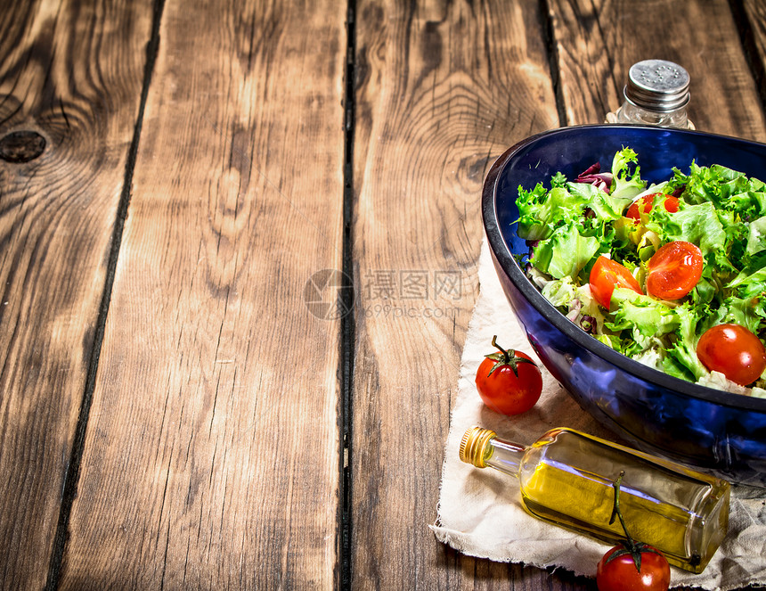番茄加沙拉和含橄榄油的新鲜绿菜在木制桌上沙拉加番茄和绿色图片