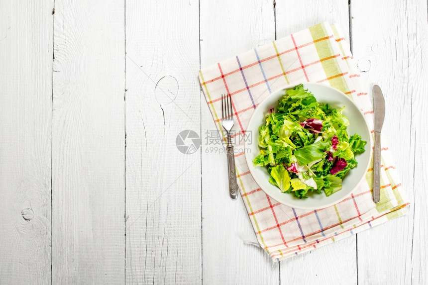 餐巾纸上新鲜绿色的沙拉白木背景纸巾上新鲜绿色的沙拉图片