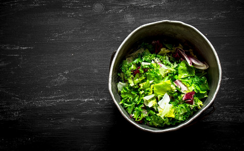 黑木桌的旧锅里有新鲜沙拉绿色旧锅里有新鲜的沙拉绿色图片