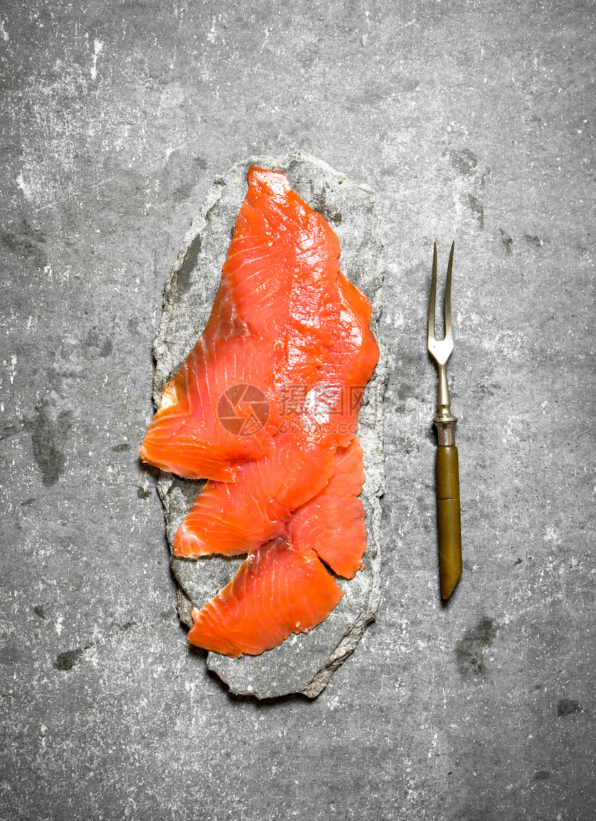 薄片的烟熏鲑鱼叉子在石头背景上叉子图片