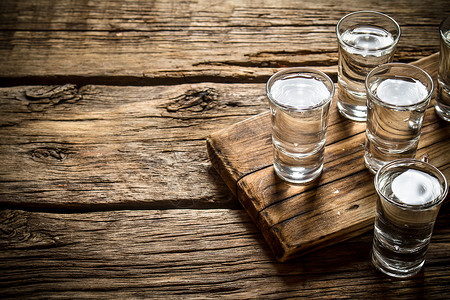 杯子和伏特加在旧板上木头背景高清图片