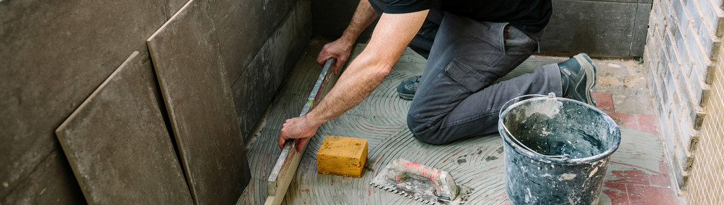 砖匠用一个关卡检查地板安装瓷砖图片