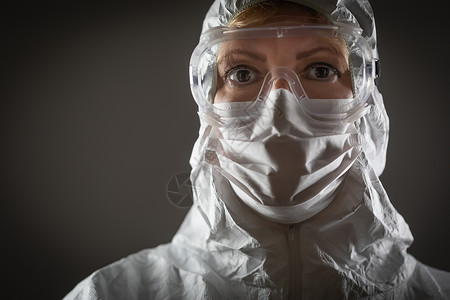 身戴保护面罩和在黑暗背景下装具的女医务工作者图片