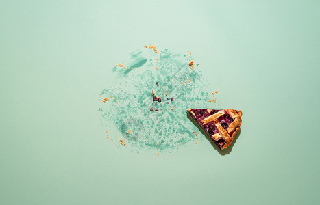 上方的绿色桌子最后一块蓝莓薄饼派上面是薄饼土烤的薄饼绿纸板上的薄饼碎屑和油脂痕迹背景图片