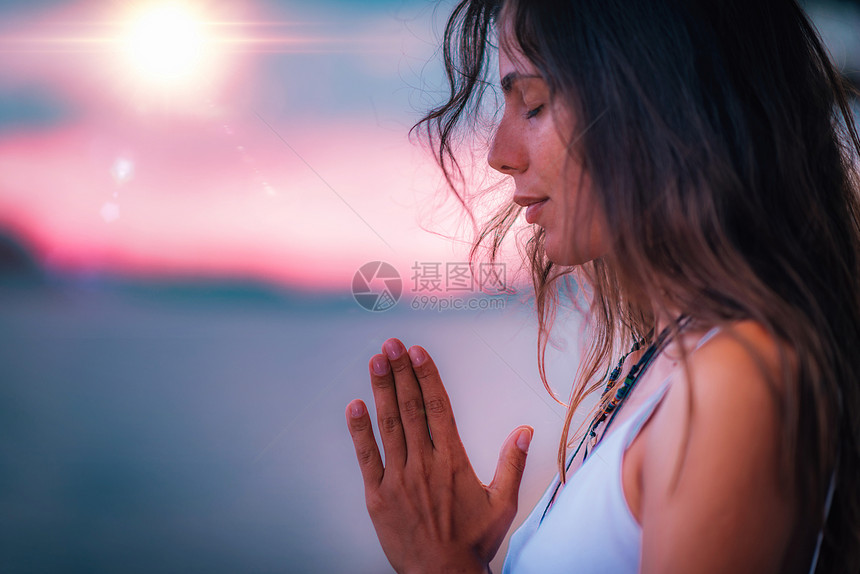 年轻女闭着眼睛冥想手握祈祷姿势进行瑜伽图片
