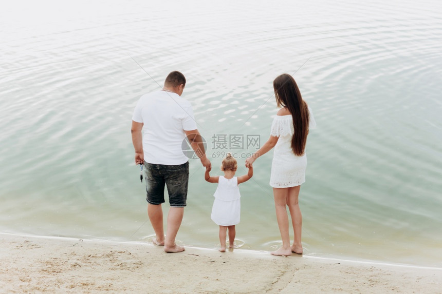 妈爸抱女儿在湖边的海滩上散步图片