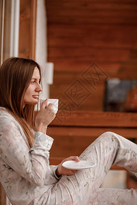 穿睡衣的女子早上在阳台喝咖啡或茶图片