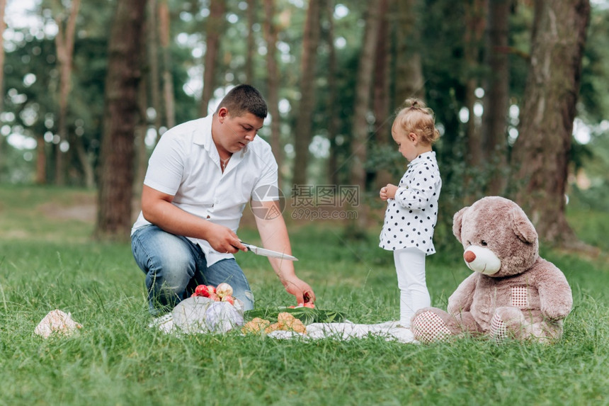 夏日在公园野餐时年幼的父亲切西瓜图片