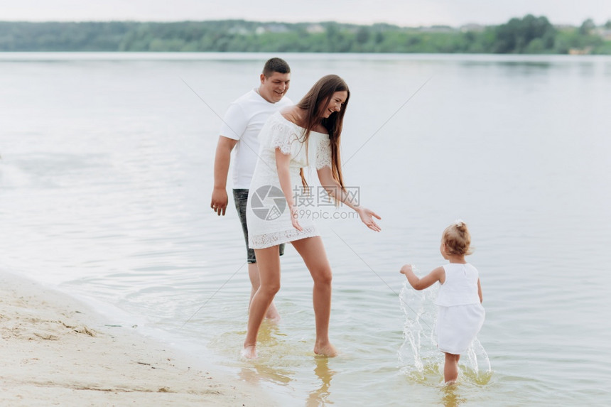 妈爸抱女儿在湖边的海滩上散步图片