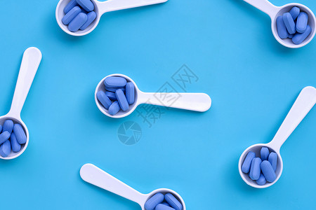 蓝色背景白塑料勺的蓝色医疗药丸图片
