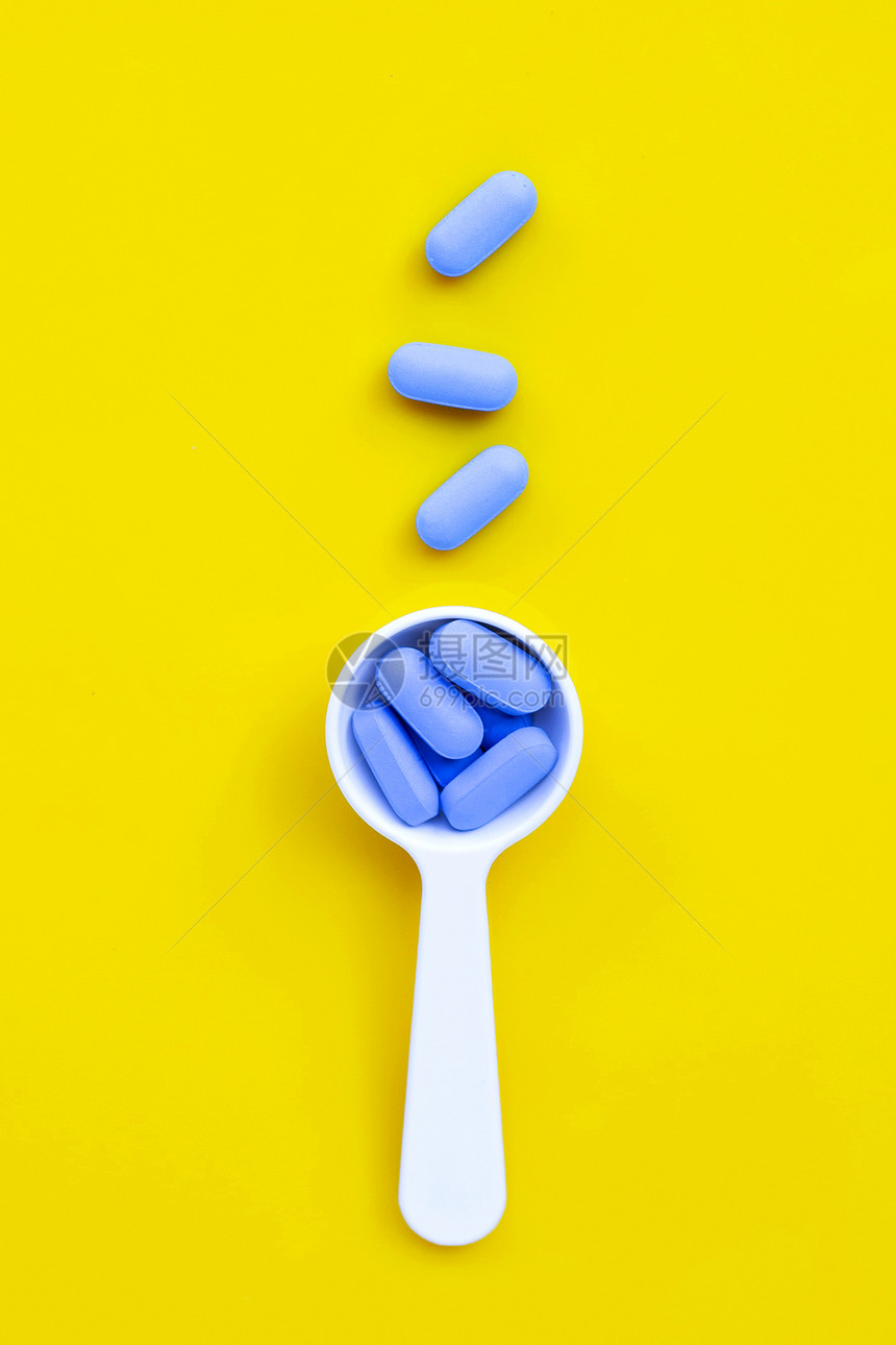 黄底带白塑料勺的蓝色医疗药丸图片
