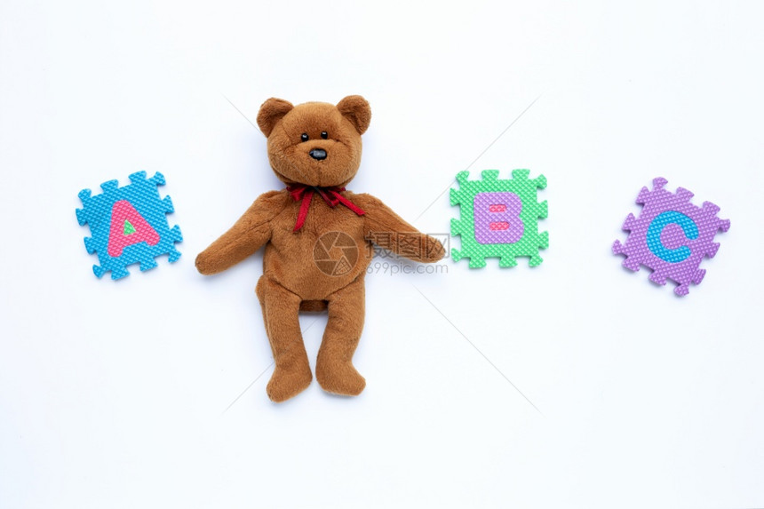 白色背景上带有英文字母拼图的褐色熊玩具教育概念复制空间图片