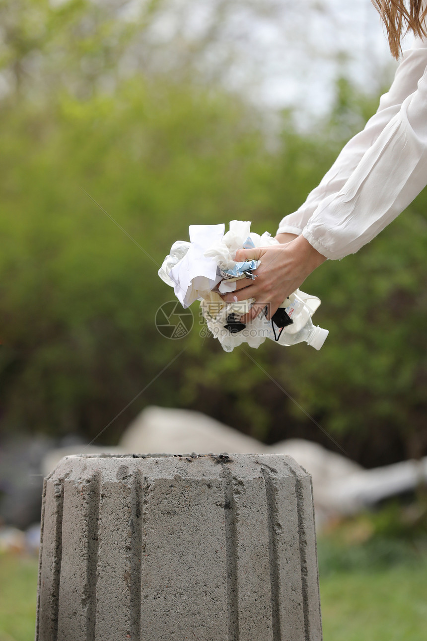 妇女把塑料垃圾扔进桶中妇女手捡垃圾塑料在公园打扫大流行病后收集垃圾有选择地关注妇女拿垃圾塑料在公园打扫大流行病后收集垃圾图片
