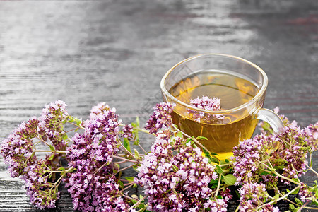 杯子里的香草茶木板底的鲜粉红花朵图片