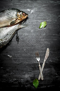 有餐具和叶的生鱼黑木本底有餐具和叶的生鱼图片