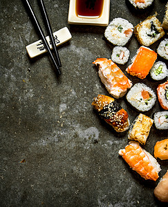 寿司卷和海鲜酱油放在石板上图片