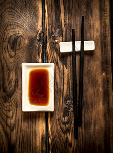 寿司的酱油和筷子木制背景的酱油和筷子的寿司图片