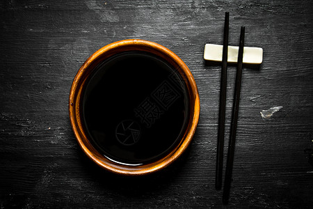 碗里的酱油和筷子黑木背景的图片