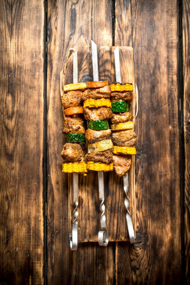 猪肉和蔬菜的串放在木制背景上猪肉和蔬菜的串图片
