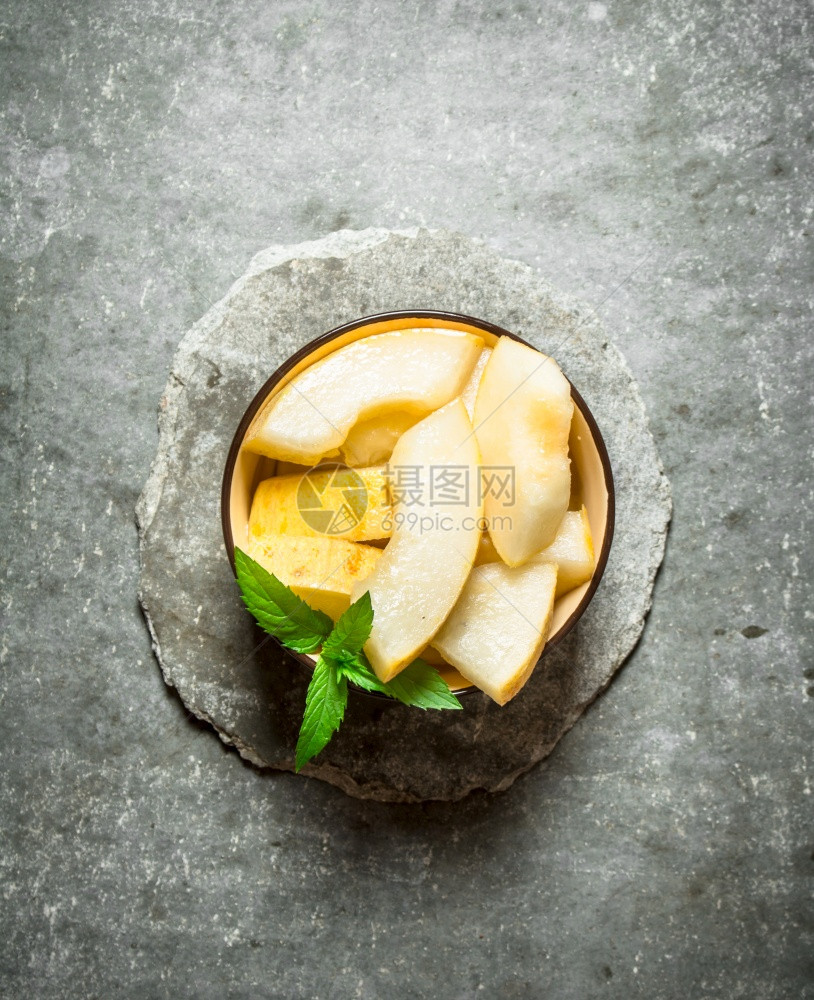 一块成熟的甜瓜薄荷枝子在石头背景上图片