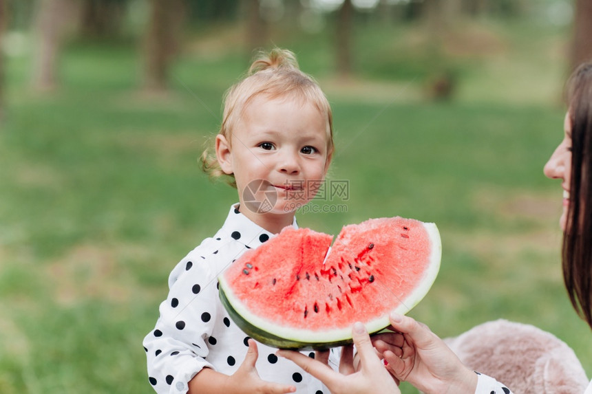 快乐的母亲和女儿在夏季公园吃西瓜快乐的笑脸家庭在公园吃西瓜母亲和女儿一起度过时间饮食维生素健康食品概念选择关注饮食健康品概念选择图片