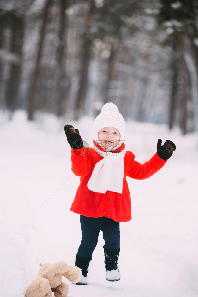 穿着红大衣的小女孩和一只泰迪熊在冬天玩得开心女孩在雪地玩耍女孩在冬天玩得开心图片