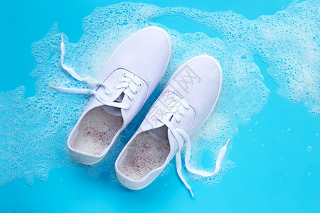 穿运动鞋在蓝色背景下涂上粉末净化水溶解的泡沫洗脏鞋图片