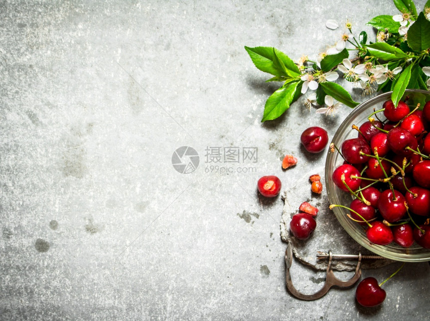 杯子上的红樱桃和金属工具石头桌上的红樱桃图片