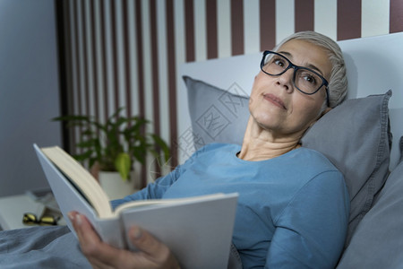睡觉老年妇女躺在床上睡前看书睡觉老年妇女睡前在床上看书图片