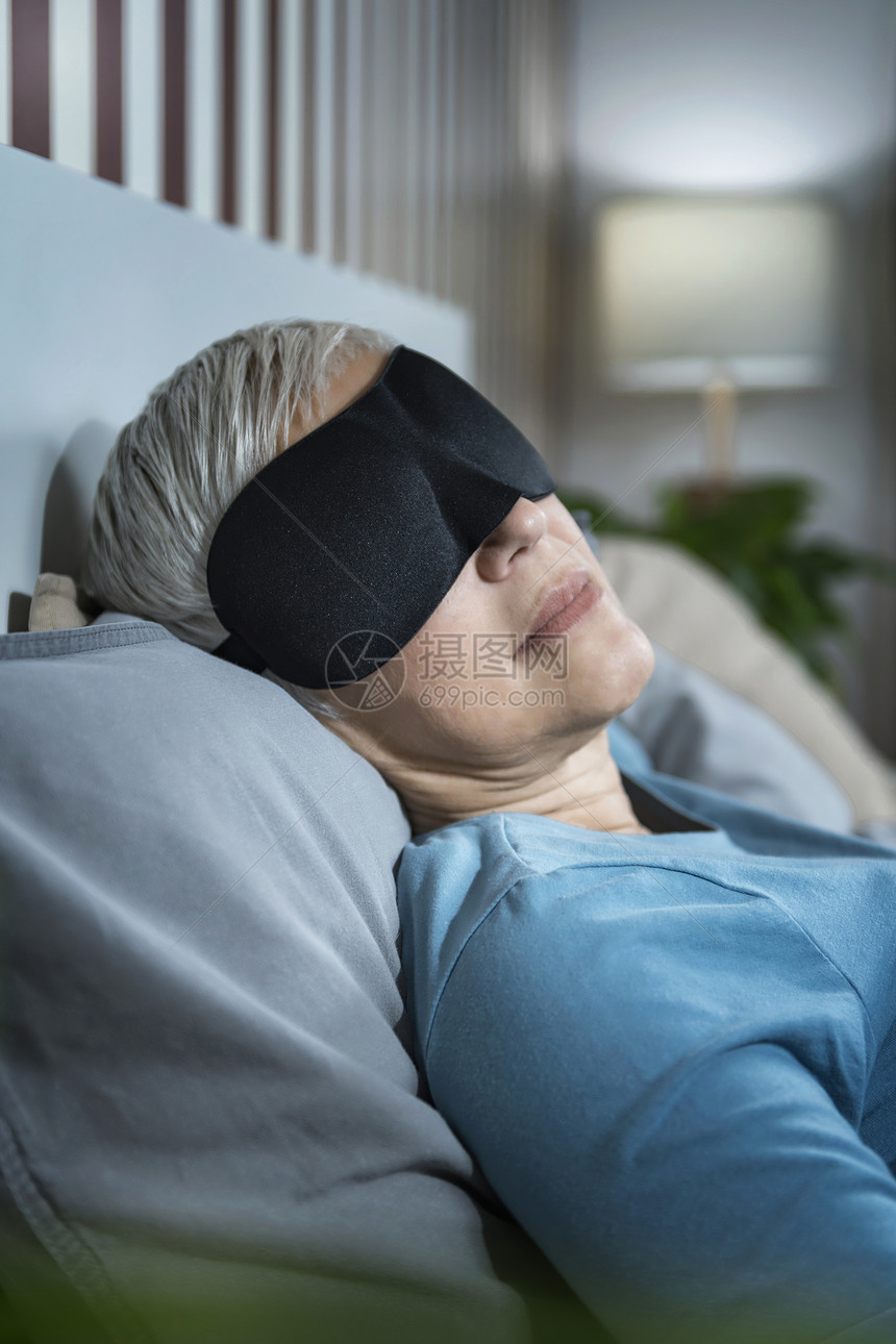 身戴黑睡面具躺在卧室床上的成年妇女身戴黑睡面具躺在床上的成年妇女图片
