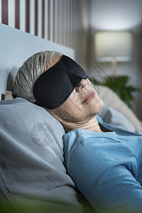 身戴黑睡面具躺在卧室床上的成年妇女身戴黑睡面具躺在床上的成年妇女背景图片