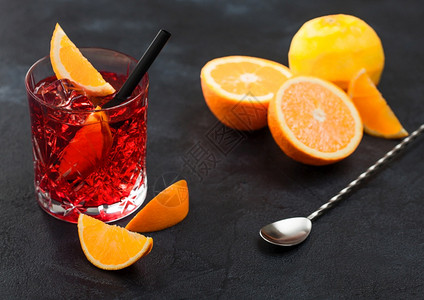 晶玻璃中的白葡萄鸡尾酒有橙片和新鲜的生子黑底勺上有子图片